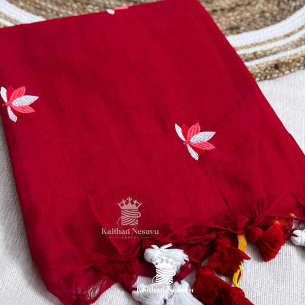 Red saree with white floral embroidery and tassels on a textured surface