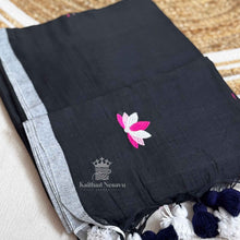 Black saree with pink and white floral embroidery on a textured surface