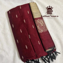 Handloom maroon cotton saree with gold zari border and leaf motifs, folded on white fabric.