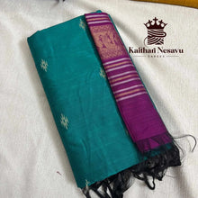 Handloom cotton saree in teal with purple pallu and gold zari work, folded on fabric