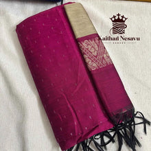 Handloom pink silk saree with gold zari border and tassels, folded on a white fabric