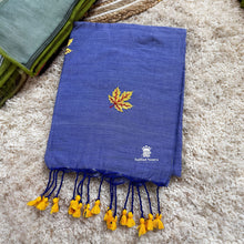 Blue saree with yellow leaf design and tassels on a textured surface