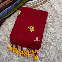 Red saree with yellow leaf design and tassels on a textured surface