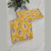 Yellow cotton saree blouse with floral vine motifs on white background, folded on fabric