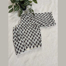 Handloom cotton blouse with black and red floral pattern on white fabric, displayed on beige surface