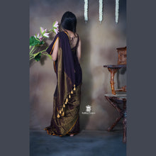 Woman in a traditional saree facing against a textured wall.