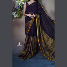 Woman wearing a dark purple and gold saree with a floral background
