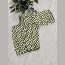 Green and white zigzag patterned cotton saree blouse displayed on cream fabric