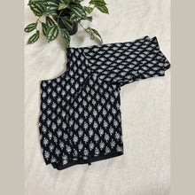 Black cotton blouse with white traditional handloom pattern, laid flat on cream fabric