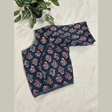 Navy blue cotton saree blouse with red and white floral pattern, displayed on fabric background