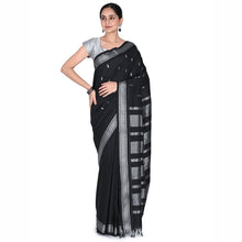 Woman wearing a black saree with silver border on a white background