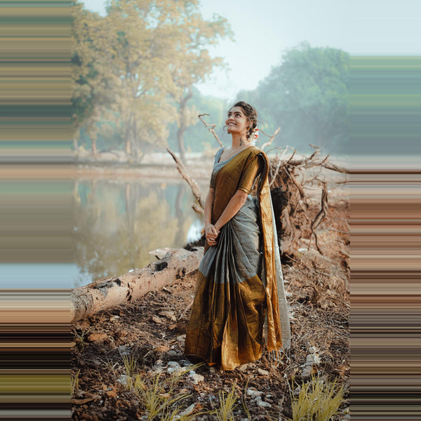 Woman in a traditional outfit standing by a lake with trees in the background
