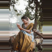 Woman in a traditional outfit sitting outdoors with greenery in the background