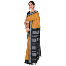 Woman wearing a mustard yellow saree with black and white patterns on a white background