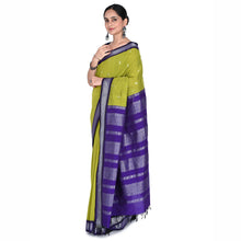 Woman wearing a green and purple saree with a white background